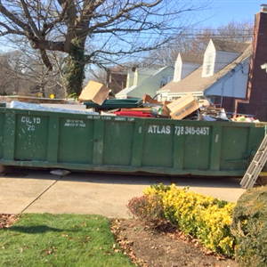 Dumpster container with garbage in a driveway